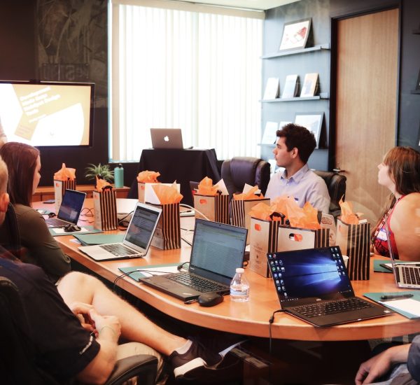 man standing in front of people sitting beside table with laptop computers